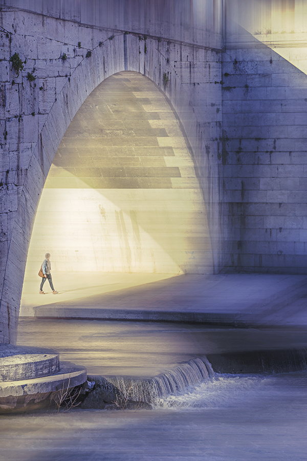 a woman walks under bridge ponte cestio in rome alongside the tiber river