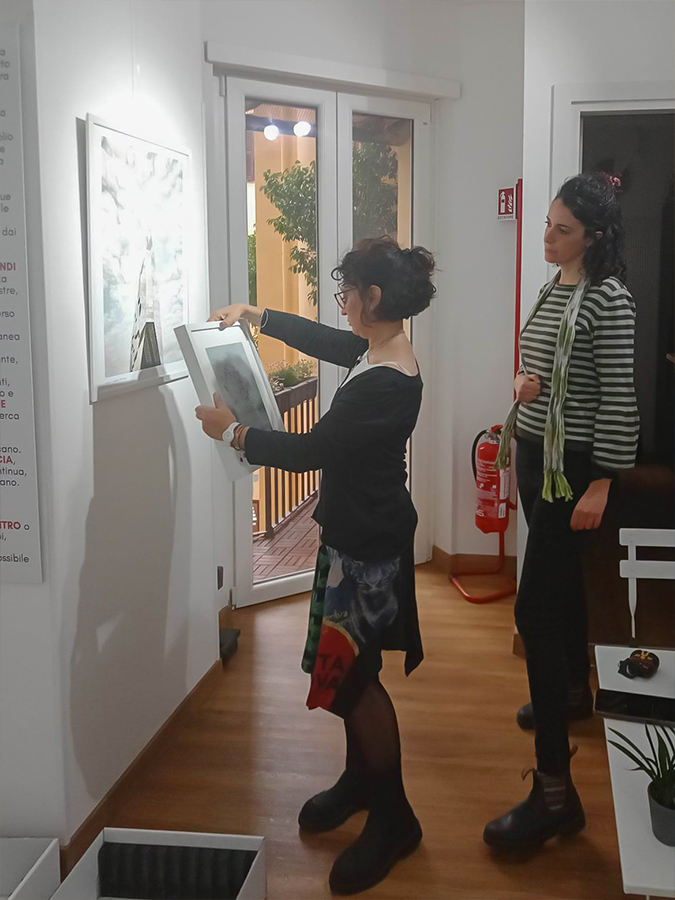 Simona Ottolenghi (left) and Daria Bruni (right) curating the exhibition - photographer Massimo Valentini's works are the images hanging on the walls